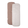 Two long, rectangular Makemake Organics Organic Cotton Muslin Burp Cloths - Blush Oat & Pecan displayed vertically, one in light beige and the other in soft pink, each with a textured cover and a visible tag on the shorter end.