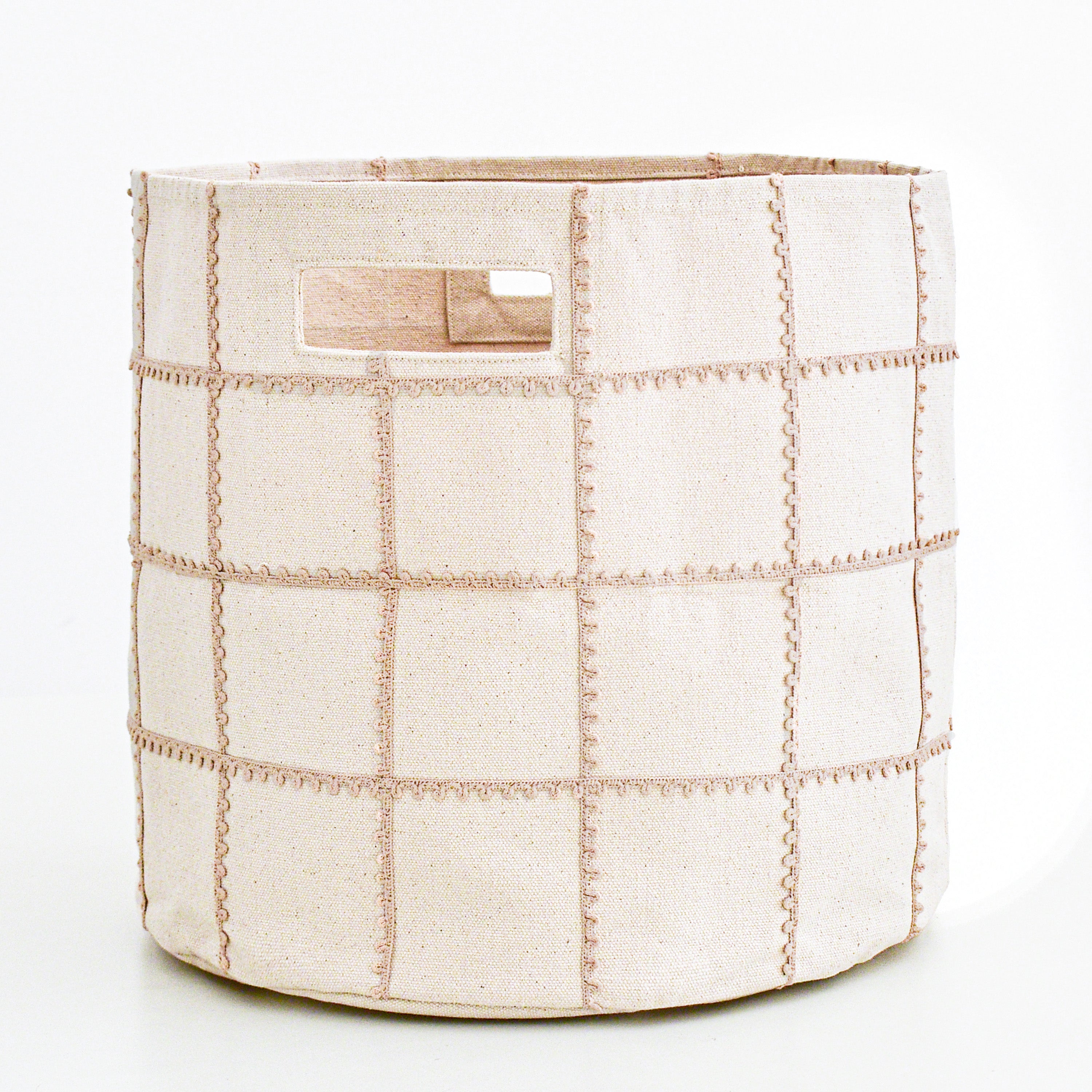 A cylindrical fabric storage bin with visible stitching, creating a grid pattern, stands against a plain white background. The Makemake Organics Storage Basket Mesh Lace - Taupe features a small fabric handle on its side.