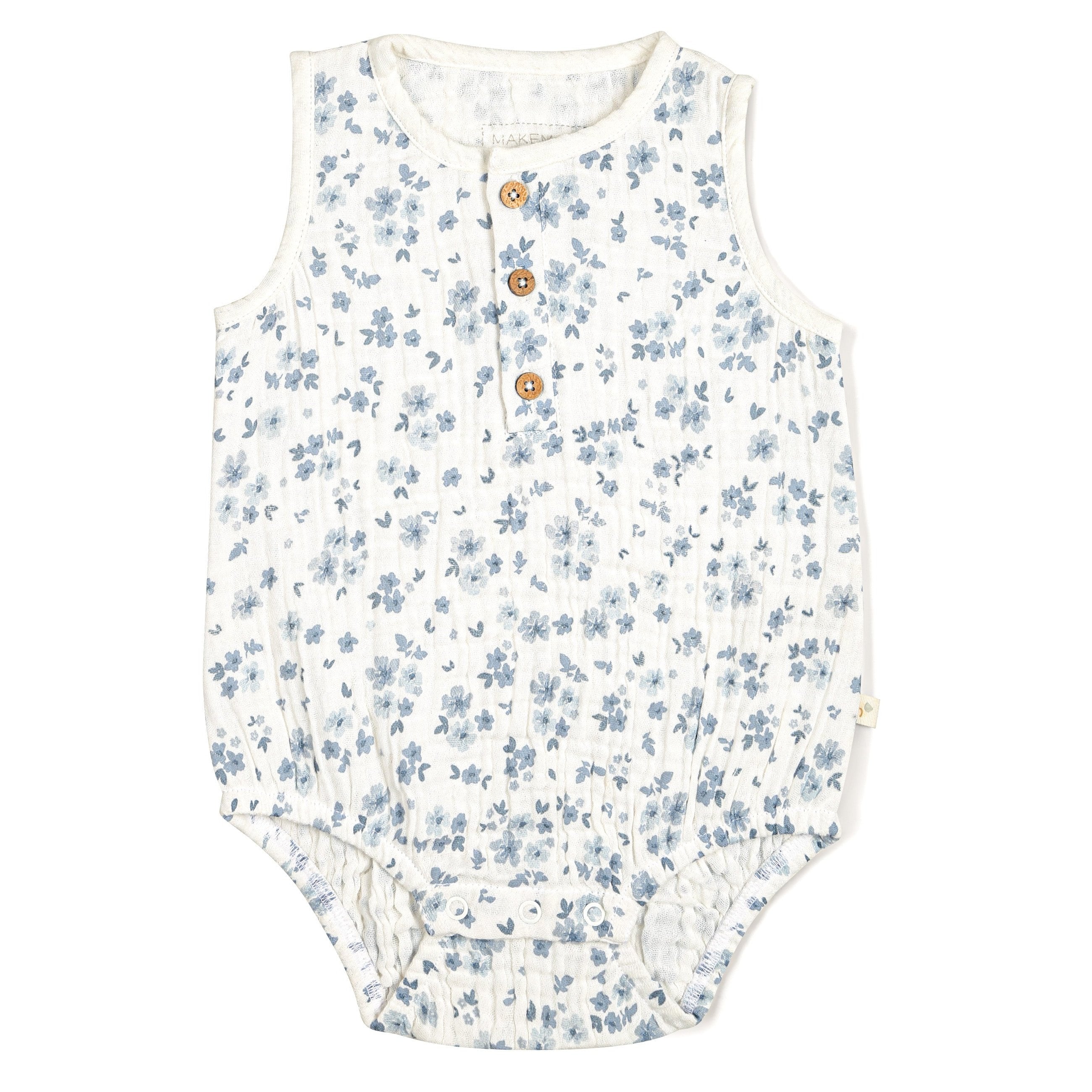 A sleeveless Organic Muslin Bubble Onesie in Periwinkle with blue floral patterns on a white background, featuring three wooden buttons and ruffled leg openings, perfect for a toddler girl by Makemake Organics.