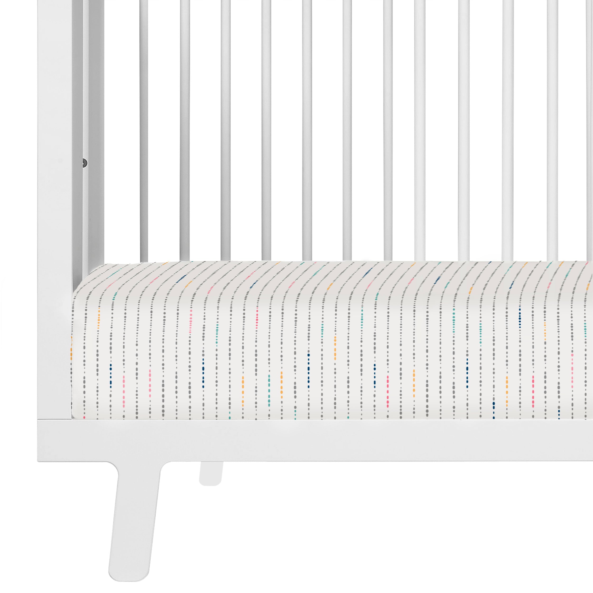 Close-up view of a white Makemake Organics crib with a dotted mattress, showing clean, sleek lines and a minimalist design.