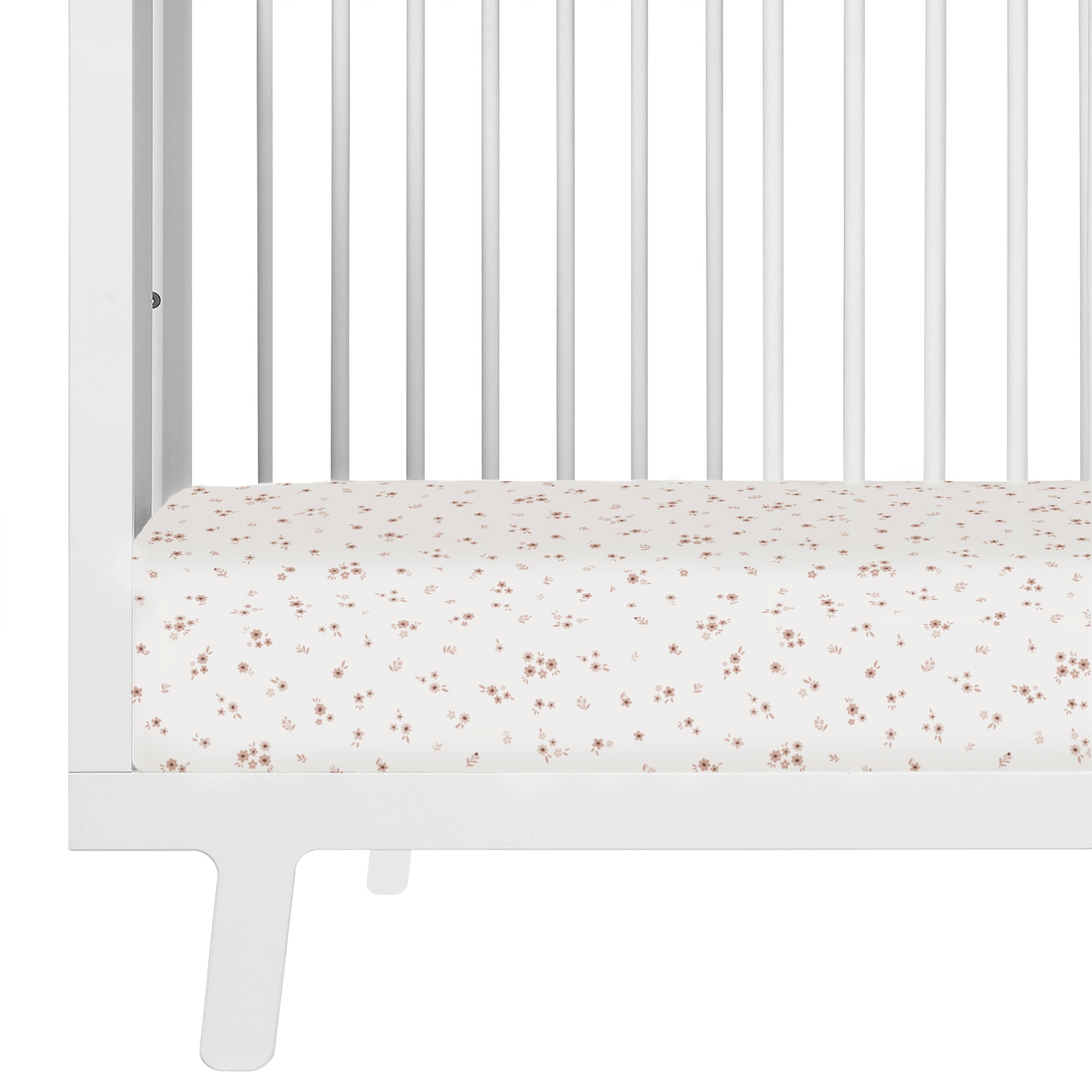 Close-up of a white baby crib with a mattress covered in a pale fabric featuring a small, delicate floral pattern. the frame and bars of the crib are sleek and modern in design with Makemake Organics' Crib Fitted Sheet with Pillowcase - Bloom.
