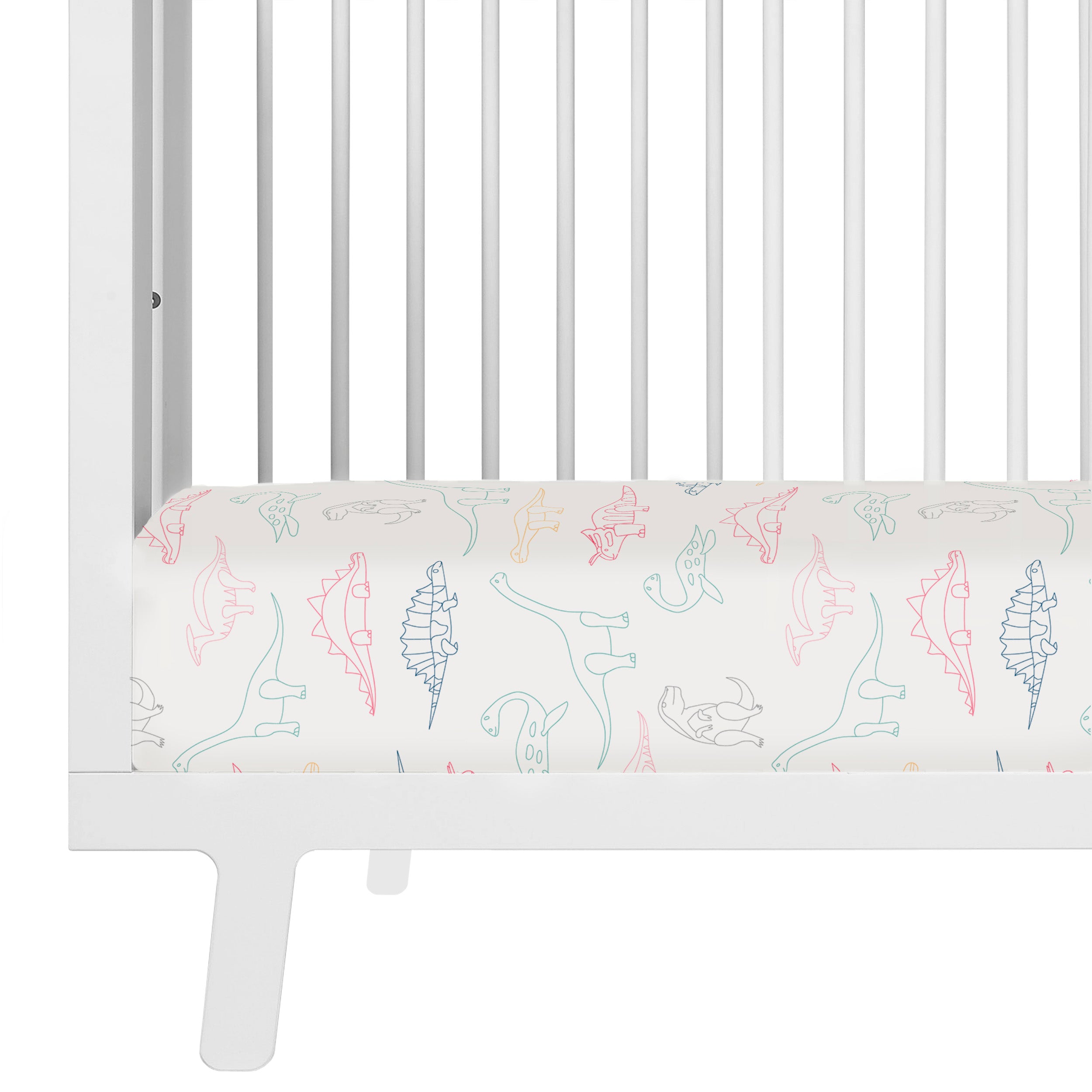 Close-up view of a white crib with a mattress covered in a Crib Fitted Sheet with Pillowcase - Dino Park by Makemake Organics featuring colorful dinosaur illustrations.