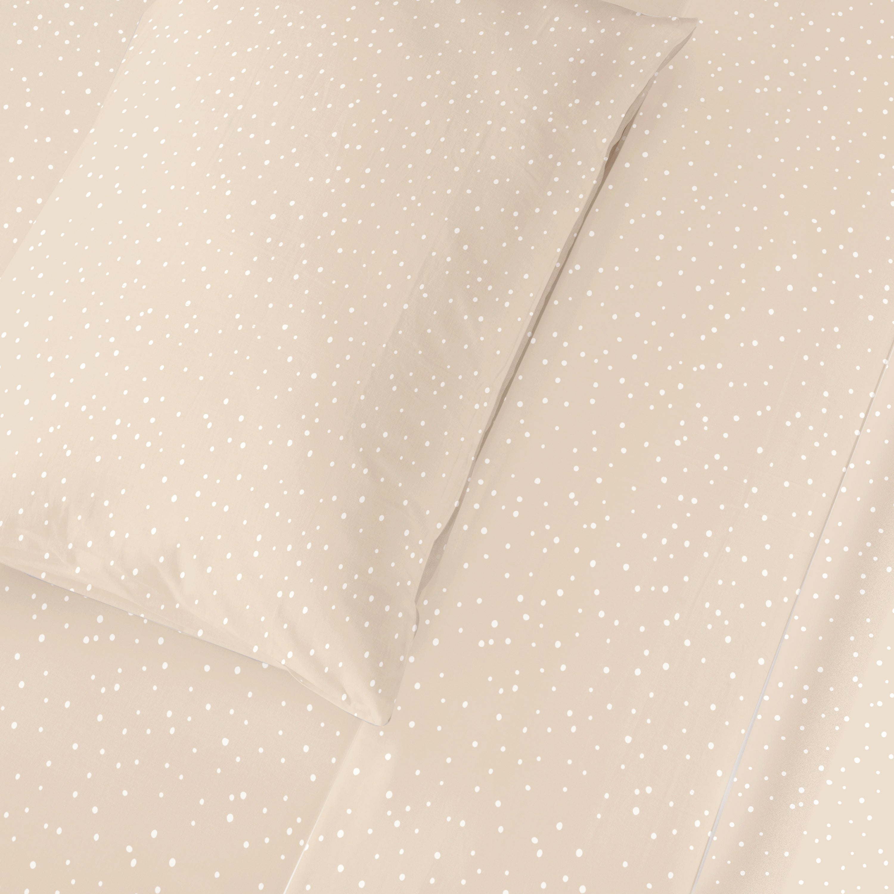 Two beige pillows with a dotted pattern on a Makemake Organics Organic Cotton Sheet Set in Polka Dots, arranged neatly and viewed from above.
