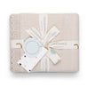 A neatly folded Makemake Organics beige organic cotton scalloped baby blanket with a stylish gift presentation, featuring a cream ribbon, branded tags, and a card with polka dots.