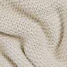 Close-up of a textured, white Chunky Knit Throw Blanket - Vanilla Natural from Makemake Organics showing detailed stitching patterns with interwoven yarns, creating a cozy and soft appearance.