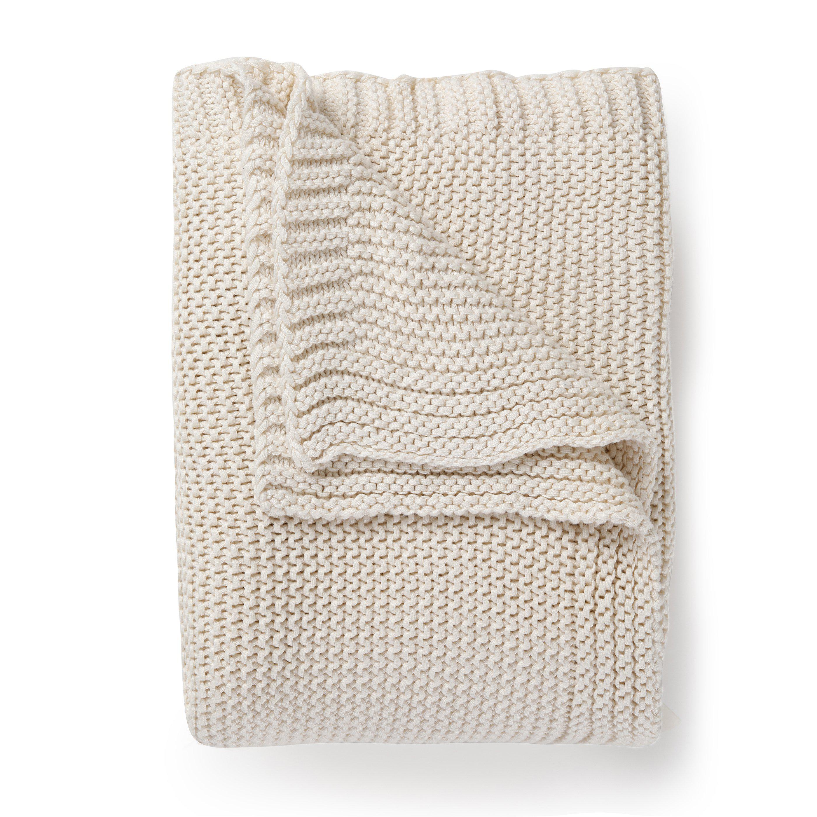 A neatly folded Vanilla Natural chunky knit throw blanket by Makemake Organics isolated on a white background.