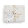 A neatly folded Organic Cotton Pointelle Baby Blanket in off-white with a tree print, tied with a patterned ribbon and a gift tag, presented on a white background.