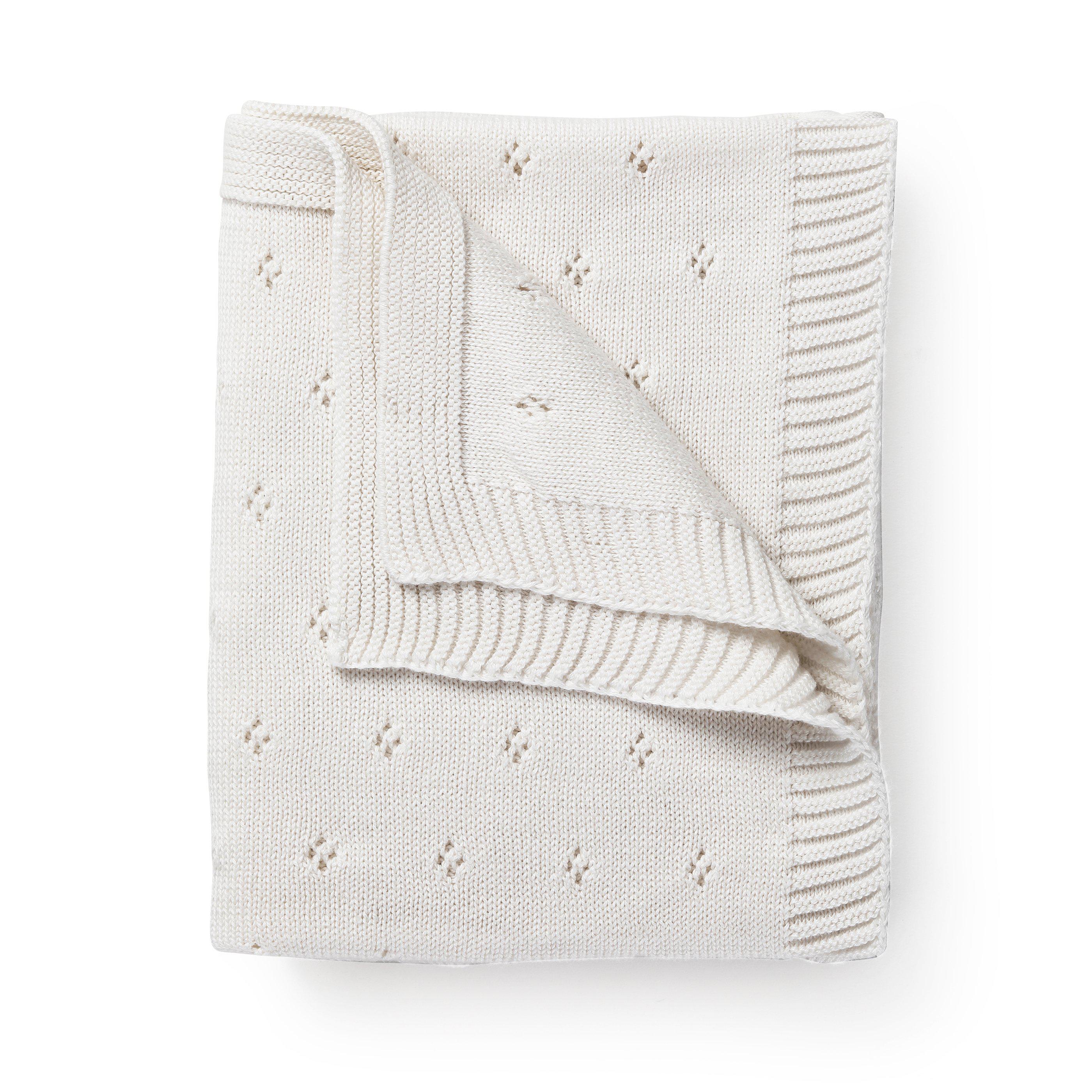 A neatly folded Organic Cotton Pointelle Baby Blanket in Ella Ivory, by Makemake Organics, with a decorative pattern of small flowers, displayed on a white background.