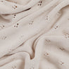 Close-up of a textured cream-colored knit fabric with delicate hole patterns and soft folds: Makemake Organics' Organic Cotton Pointelle Baby Blanket in Nora Shell.