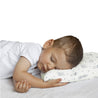 A toddler with short dark hair, dressed in a white shirt, peacefully sleeping on a Makemake Organics Organic Cotton Toddler Pillowcase - Celestial, isolated on a white background.