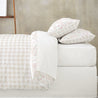 A neatly made bed with Makemake Organics' Organic Duvet Cover in Blossom & Plaid, set against a subtle grey background.