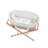 A modern Makemake Organics baby bassinet with a white quilted interior and wooden stand. a teddy bear and a blanket with animal prints are inside the Bassinet Fitted Sheet - Safari & Wild.
