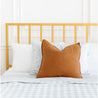 A neatly made bed with the Makemake Organics Organic Duvet Cover in Milkyway & Gingham. A large burnt orange pillow is centered in front of two standard white pillows against a yellow metal headboard.