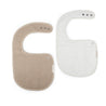 Two Organic Muslin Bibs in ivory and taupe colors, shaped like letters c and g, displayed on a white background with snap button closures visible. Brand: Makemake Organics.