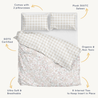 A neatly made bed featuring an Organic Duvet Cover in Blossom & Plaid by Makemake Organics, accompanied by labels highlighting attributes like plush 300 thread count, GOTS certification, and non-toxic materials.