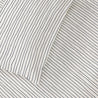 A close-up image showing a Makemake Organics Organic Cotton Fitted Sheet Set in Navy Stripes, partially folded over on one corner revealing the plain white underside.