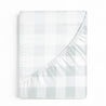A neatly folded light gray and white checked Organic Cotton Sheet Set - Gingham duvet cover seen from above, isolated on a white background by Makemake Organics.