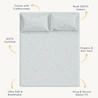Top view of a neatly made bed with Makemake Organics Organic Cotton Sheet Set in Milky Way, featuring two pillows and a speckled design. text labels highlight its eco-friendly, organic, soft, and secure qualities.