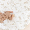 A baby's hand holds a small wooden toy on a Makemake Organics Organic Cotton Quilted Reversible Play Mat - Safari and Wild with a jungle animal print, including elephants, tigers, and various plants.