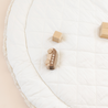 A minimalist scene with a wooden toy car and two blocks on a Makemake Organics Organic Cotton Quilted Reversible Play Mat - Blossom / Ivory set against a light background.