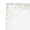 Close-up of a white Organic Cotton Changing Pad Cover - Wild by Makemake Organics, with a neutral-toned leopard print design, draped over a curved changing pad on a white background.