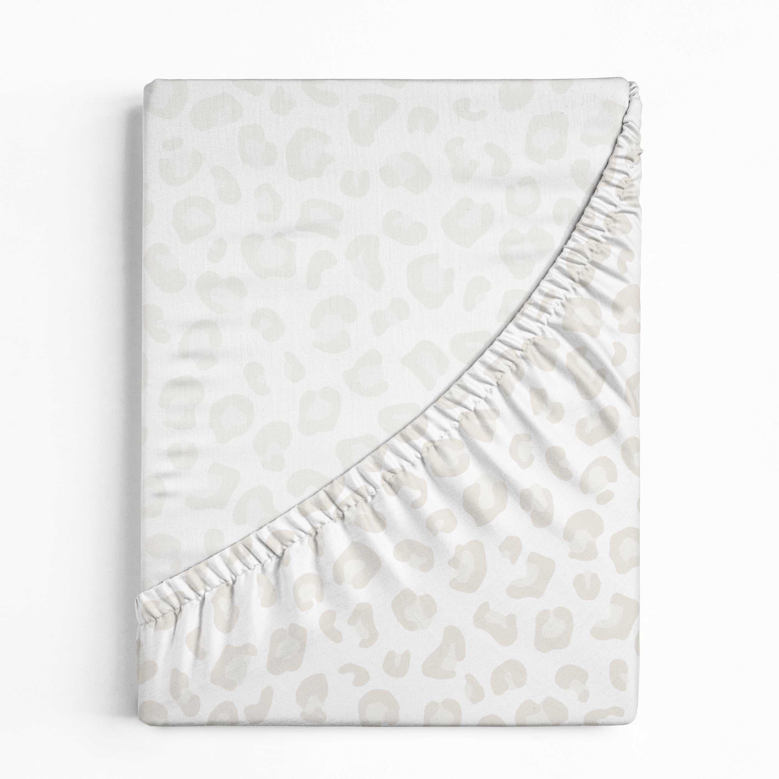 A soft, fleece Crib Fitted Sheet with Pillowcase - Wild from Makemake Organics with a subtle leopard print design, neatly folded with one corner turned down to display the fleece texture, isolated on a white background.