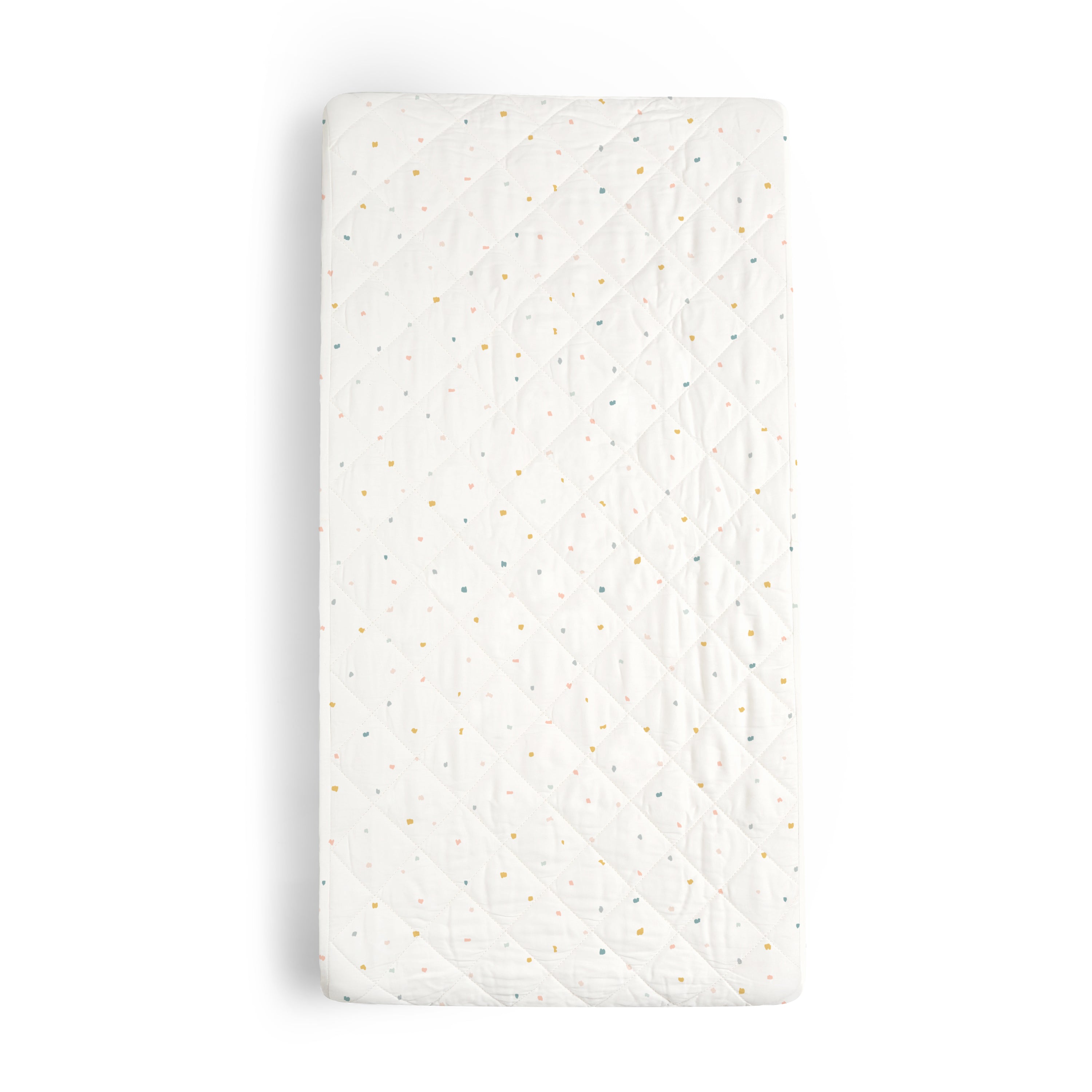 A white crib mattress with a quilted cover featuring a pattern of multicolored specks, isolated on a white background. Organic Cotton Changing Pad Cover - Dotty by Makemake Organics.