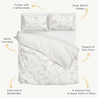 A luxurious bedding set displayed with a pillowcase, sheets, and Makemake Organics Organic Duvet Cover - Safari & Wild adorned with a soft animal and floral pattern. The image highlights features like 300tc sateen, GOTS certification, and organic material.