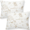 Two white Makemake Organics pillows with a beige safari animal and plant print, featuring elephants, giraffes, trees, and foliage.