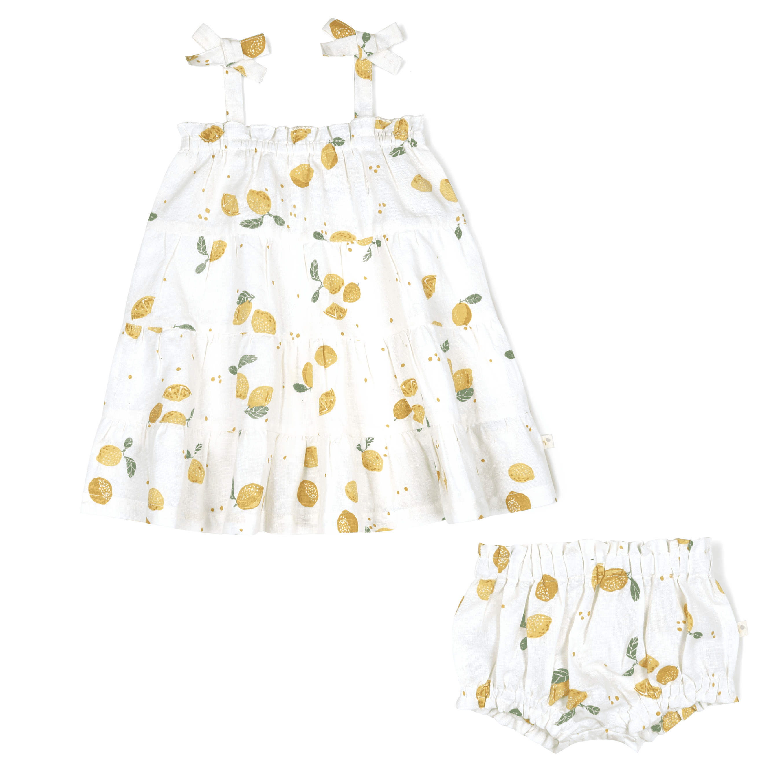 White baby's outfit with a sleeveless dress and matching bloomers, both adorned with a pattern of gold and green lemons. The Organic Linen Tiered Strap Dress - Citron features bow-tied shoulder straps and a full skirt. (Brand Name: Makemake Organics)