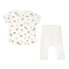 A flat-laid baby outfit consisting of a Makemake Organics Organic Tee & Pants Set in Malibu, which includes a white short-sleeve t-shirt with colorful palm tree and surfboard print, and coordinating plain white leggings.