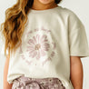 A close-up of a person wearing a beige Boxy Tee with "you are loved" text and a floral design around it. only the torso is visible, no face shown.