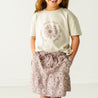 A young girl dressed in a Boxy Tee and Skort Set - Daisies from Organic Girls, standing against a plain background.