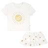 A white baby's outfit consisting of a Boxy Tee and Skort Set - Sunshine from Makemake Organics, with the phrase "good vibes" inside a yellow sun design on the t-shirt, and a matching white skirt adorned with yellow sunflowers.