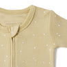 A close-up of a beige Organic 2-Way Zip Romper - Yellowstone with white polka dots, featuring a round neckline and a front button detail, displaying the brand "Organic Baby.