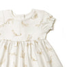 A white Organic Puff Sleeve Dress in Wildcat from Organic Kids with a subtle pattern of golden giraffes, featuring ruffled sleeves and a gathered waist, displayed against a plain background.