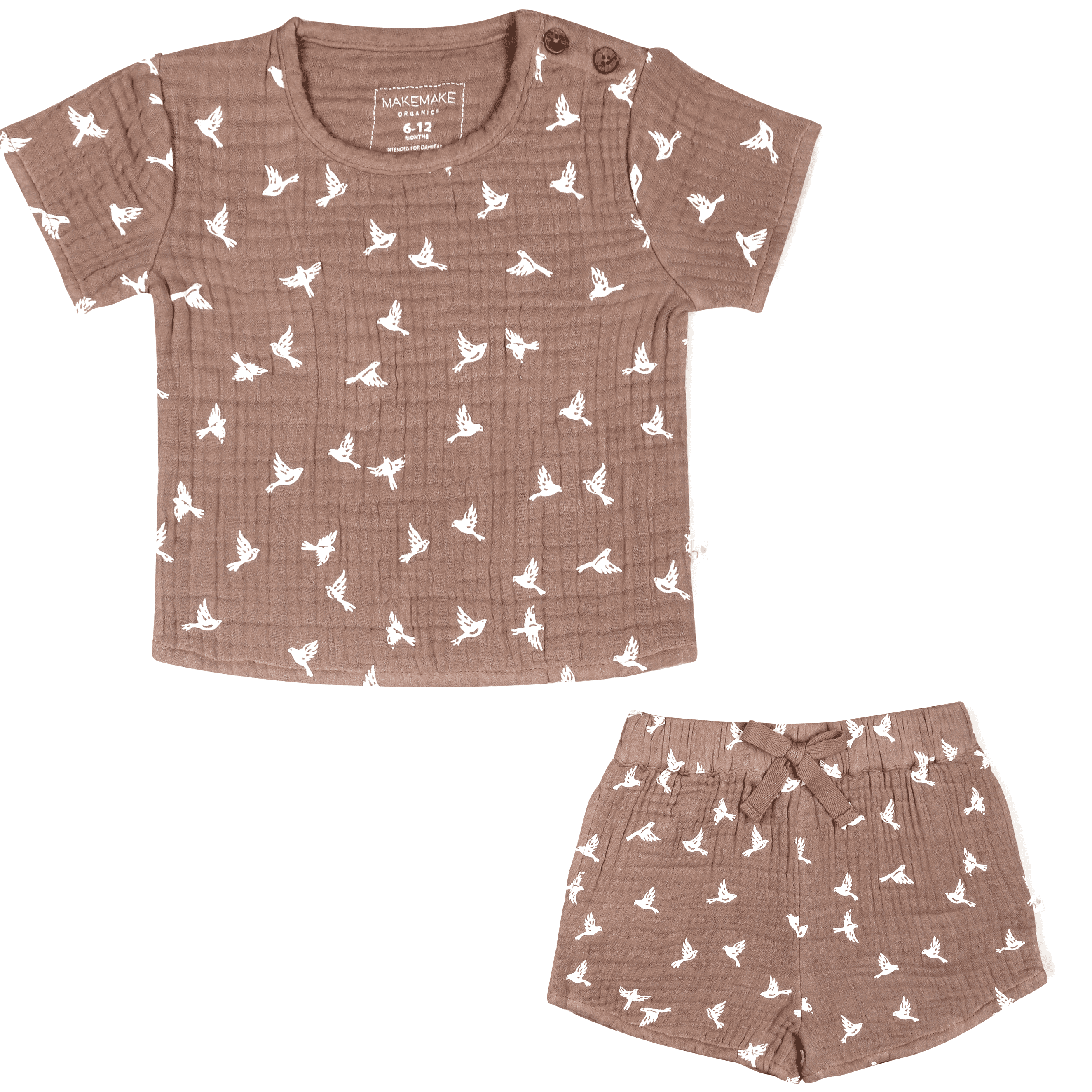 A brown children's outfit featuring Makemake Organics' Organic Muslin Top and Shorts 2 Piece Set - Flock, with a short-sleeved shirt and matching shorts, both with a white bird print design. The shirt has a button at the shoulder, and the shorts have a bow at.