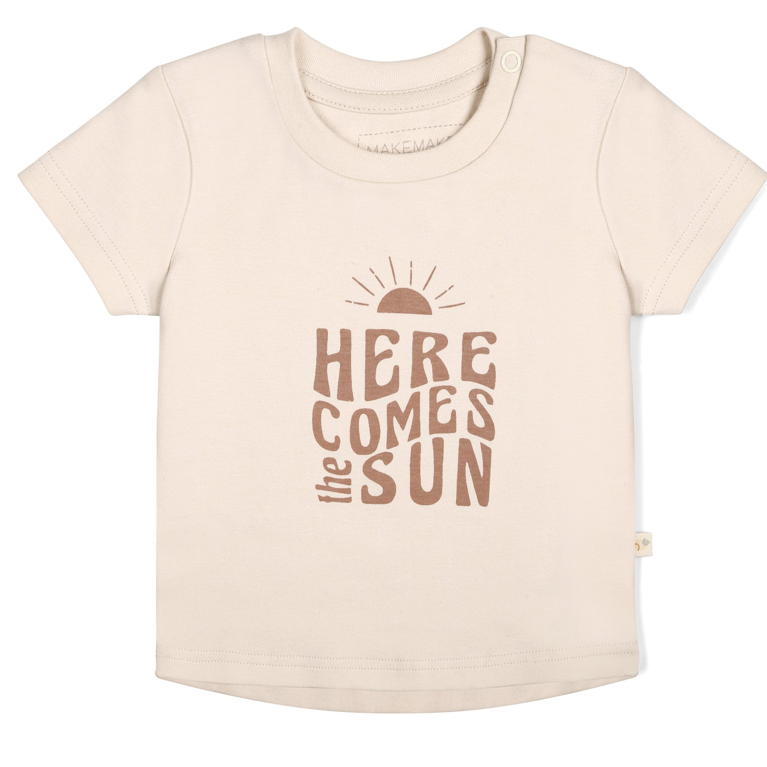A cream-colored toddler Organic Crew Neck Tee - Here Comes The Sun from Makemake Organics, with the phrase "here comes the sun" printed in brown letters, featuring a graphic of a rising sun above the text.