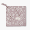 A flat-lay image of a purple baby bib with white floral pattern and the brand name "Makemake Organics" visible, featuring snap buttons for closure.