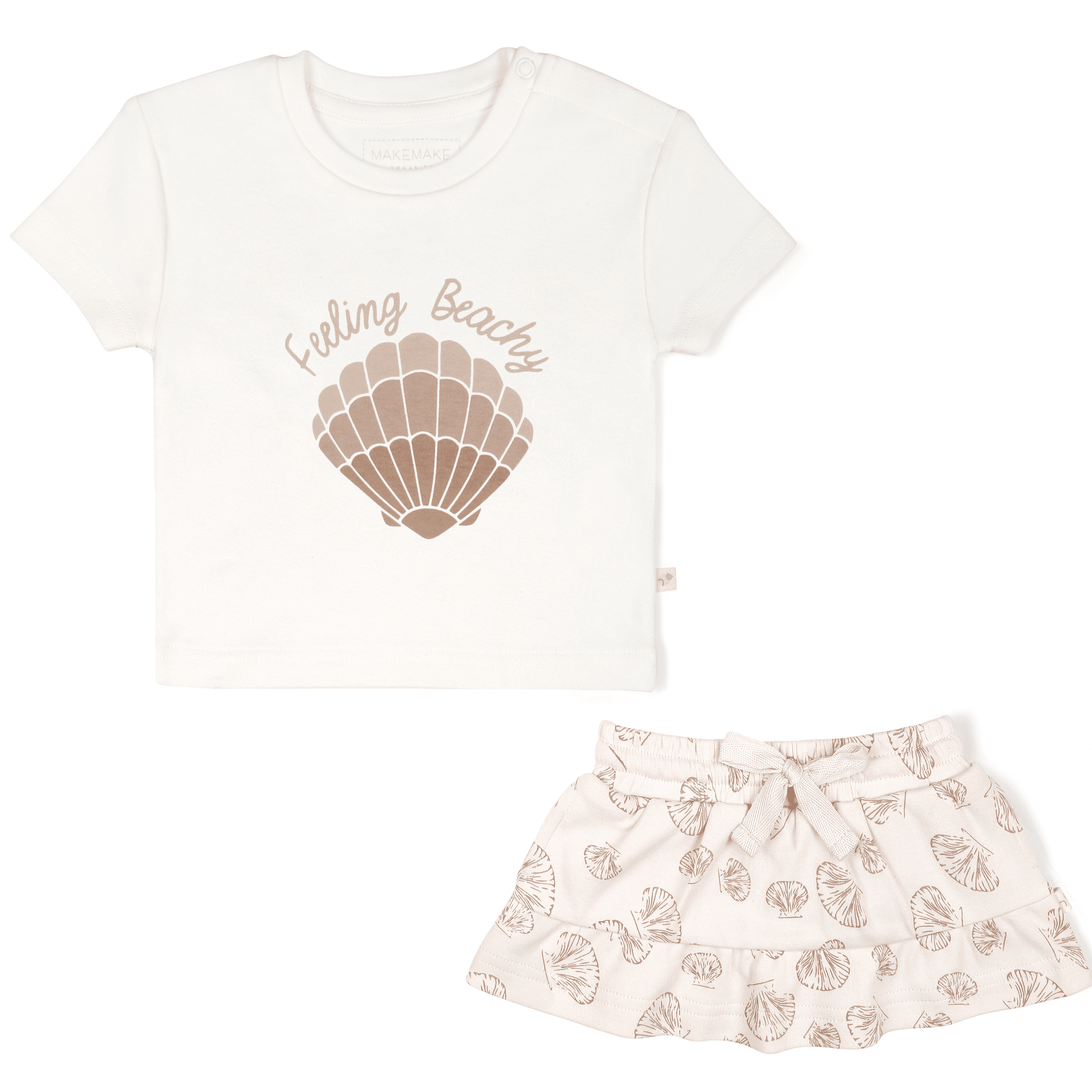 A toddler's outfit consisting of a Boxy Tee and Skort Set - Seashells from Makemake Organics, with a white t-shirt featuring the phrase "feeling beachy" and a seashell graphic paired with a pink skirt adorned with a seashell print.