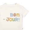 A close-up image of a Makemake Organics white toddler Organic Crew Neck Tee - Bonjour with the phrase "bon-jour!" printed in colorful letters across the chest. The shirt has a small snap button on the shoulder.