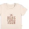 A beige toddler onesie with the phrase "here comes the sun" printed in brown, featuring a sun graphic above the text. The onesie has a round neckline and a button on the shoulder. 
Product Name: Organic Crew Neck Tee - Here Comes The Sun
Brand Name: Makemake Organics
