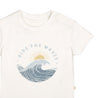 A cream-colored toddler Organic Crew Neck Tee - Ride The Waves by Makemake Organics featuring a graphic print of a wave with the sun in the background and the phrase "ride the waves" encircling the design.