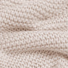 Close-up view of a Chunky Knit Throw Blanket - Nora Shell by Makemake Organics, a soft, textured white knit fabric with a detailed pattern of loops and stitches, highlighting the intricacies of the weave.