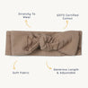 A beige, textured cotton headband with a central knot from Makemake Organics, labeled with features: "stretchy to wear", "GOTS certified cotton", "soft fabric", and Organic Headwrap - Wildwood & Evergreen Fir.