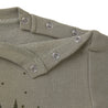 Close-up of a green shirt collar with silver snap buttons from Makemake Organics, featuring subtle star embroidery on the fabric.