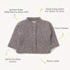 Child's gray quilted jacket from Organic Kids with white dots, featuring patch pockets, a name label, and merino wool infill, made from gots cotton, with annotations highlighting