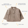 A beige, quilted Organic Merino Wool Buttoned Jacket in Mocha from Organic Kids with a high collar and front button closure. Features include a patch pocket, ample sizing for growth, and a name label.