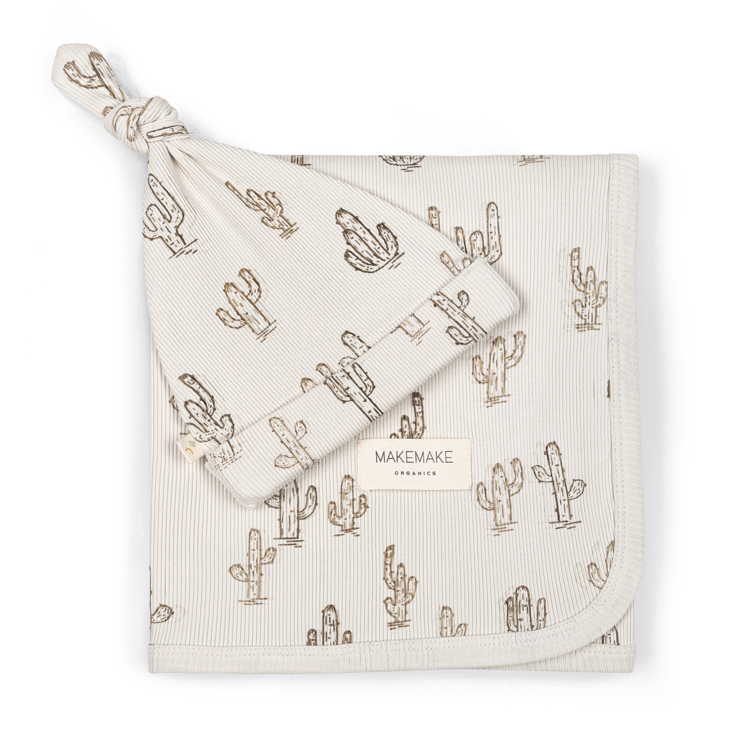 A beige Organic Swaddle Blanket & Hat with a cactus print and a corner tied into a knot, labeled "Makemake Organics." the fabric texture is soft and finely woven.