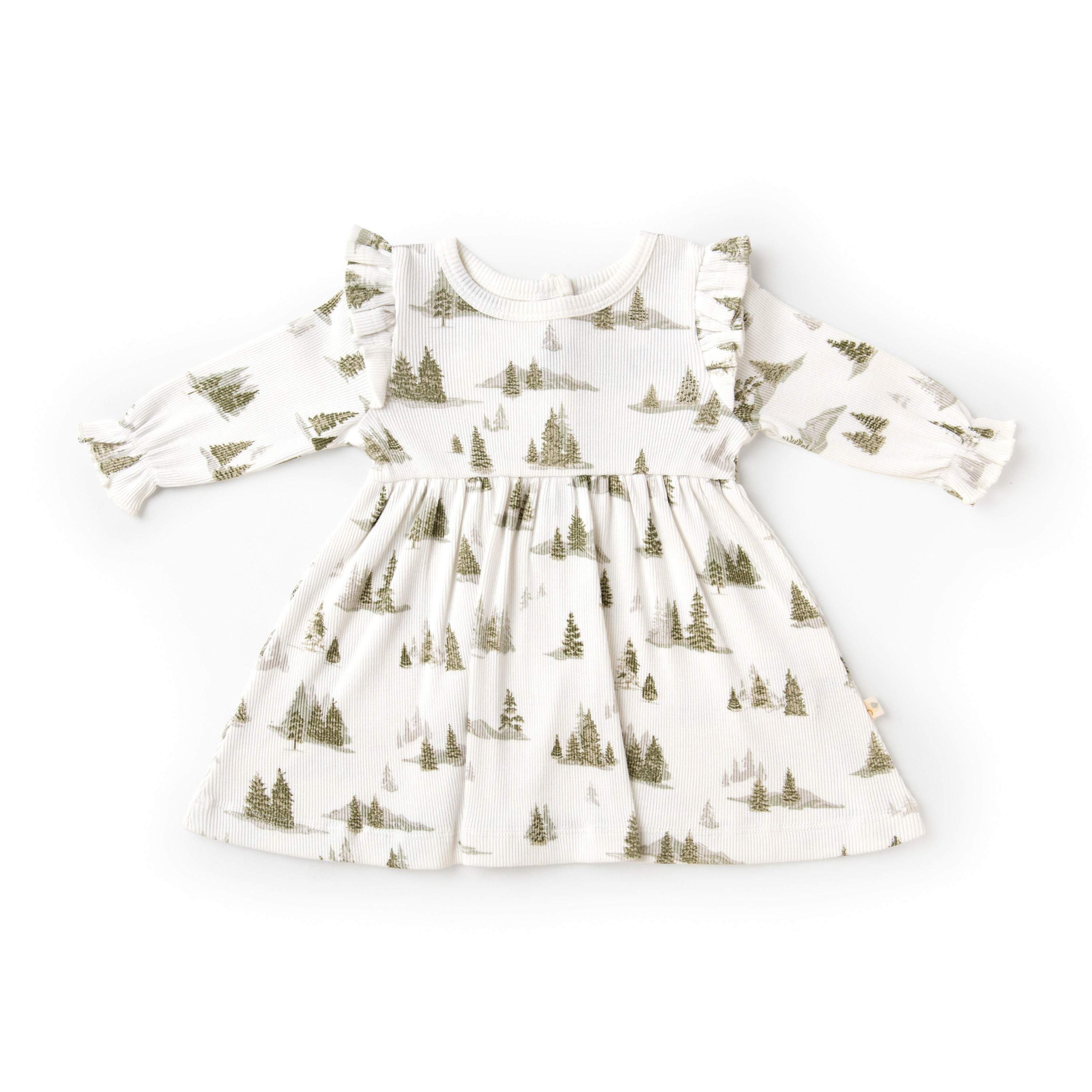 A white baby dress from Organic Girls with a woodland theme, featuring a pattern of green pine trees, long sleeves, and ruffled shoulders, displayed on a plain background.